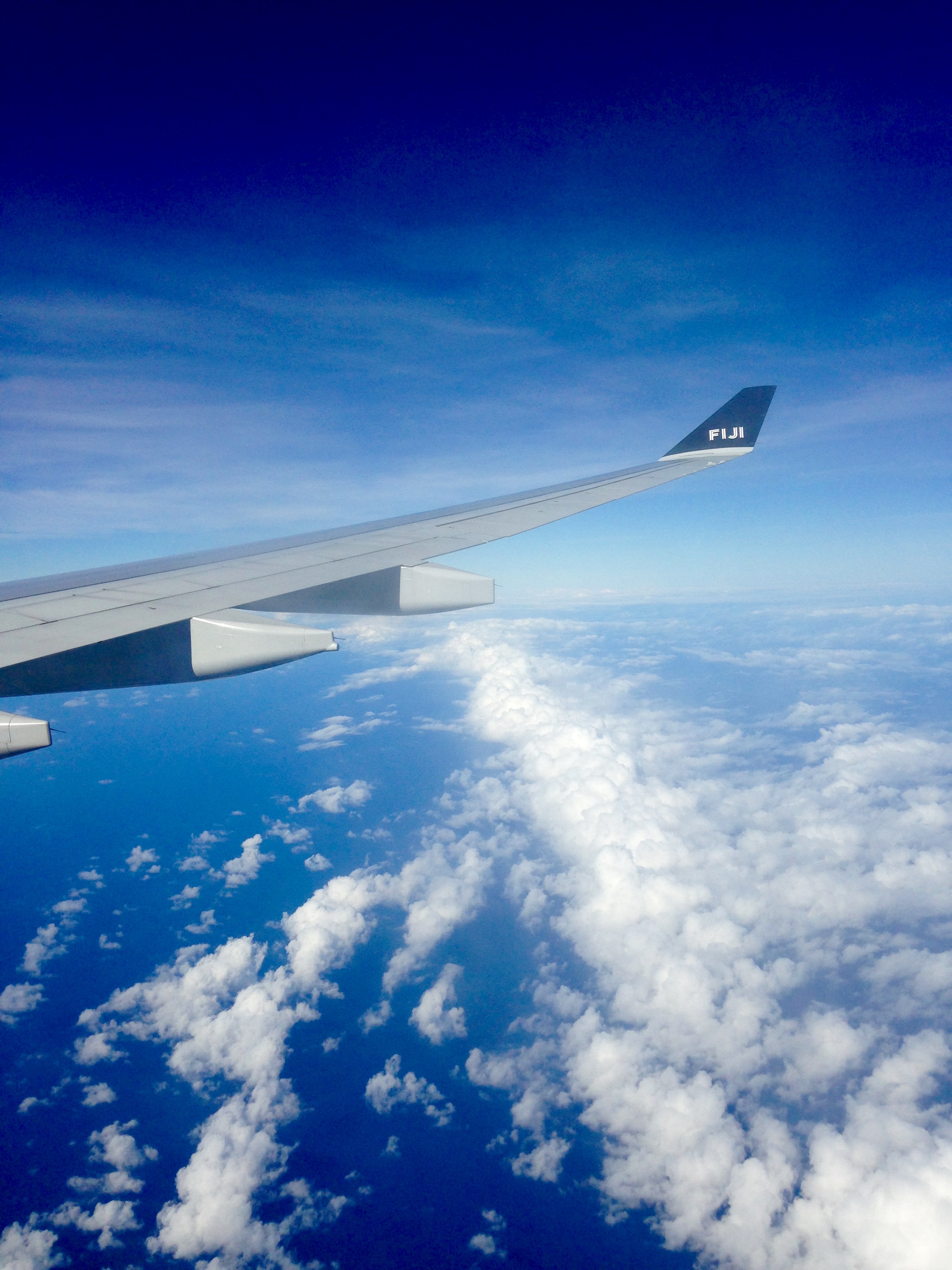 Blue skies and blue waters with a plane wing in full view on a flight from Nadi Fiji to Cairns Australia with Fiji Airways