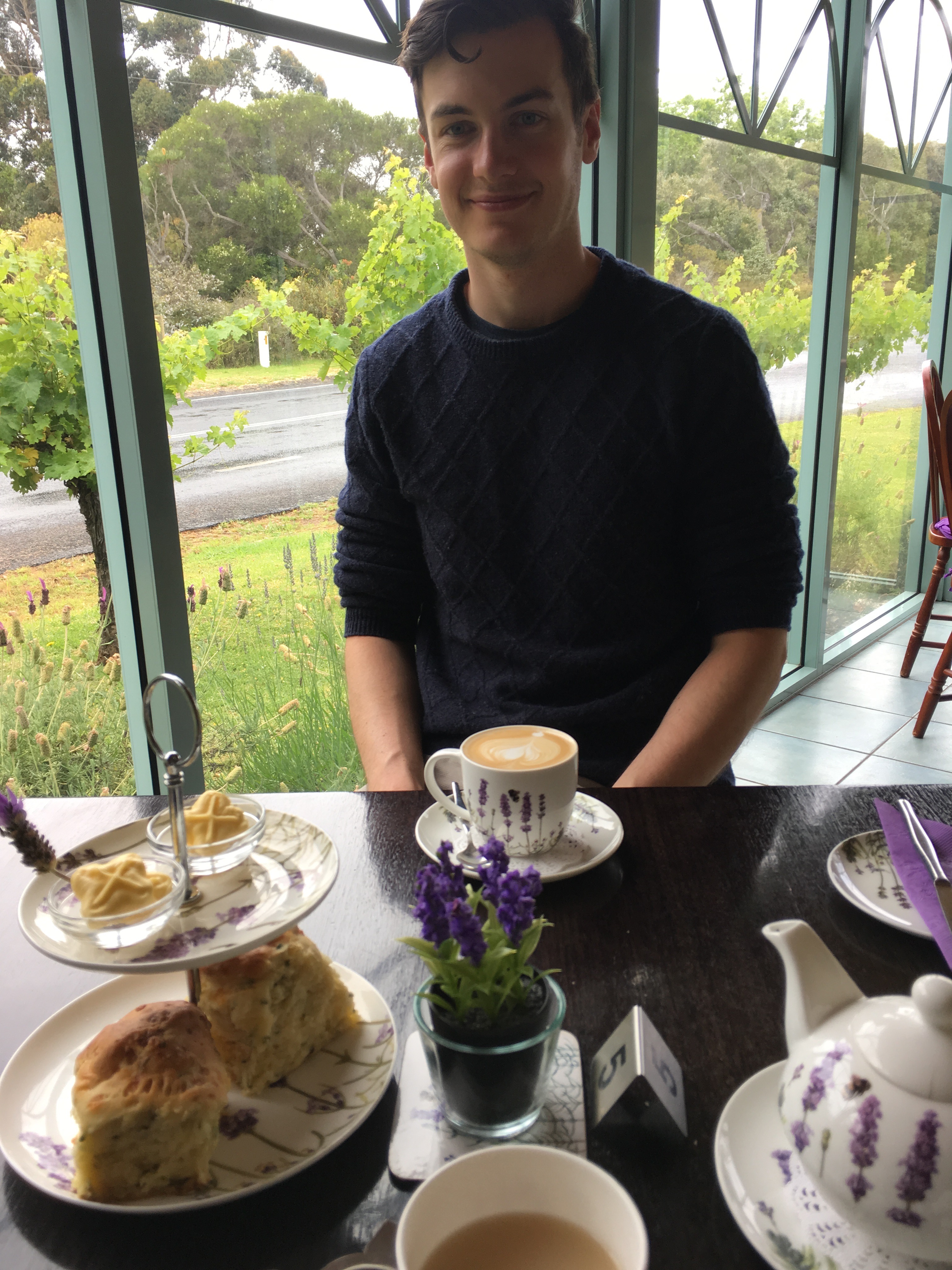 Man smiles at camera with scones and lavender tea