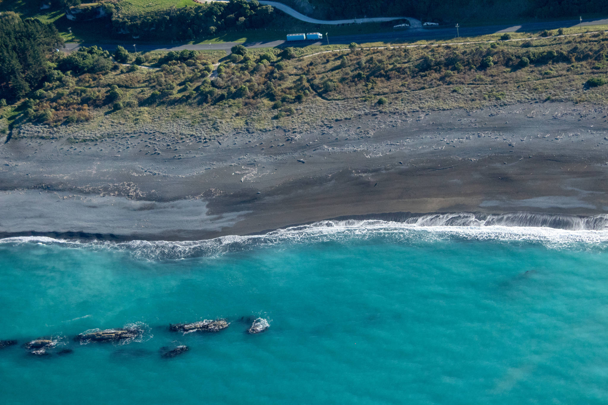coastal rocks at grey sand beach