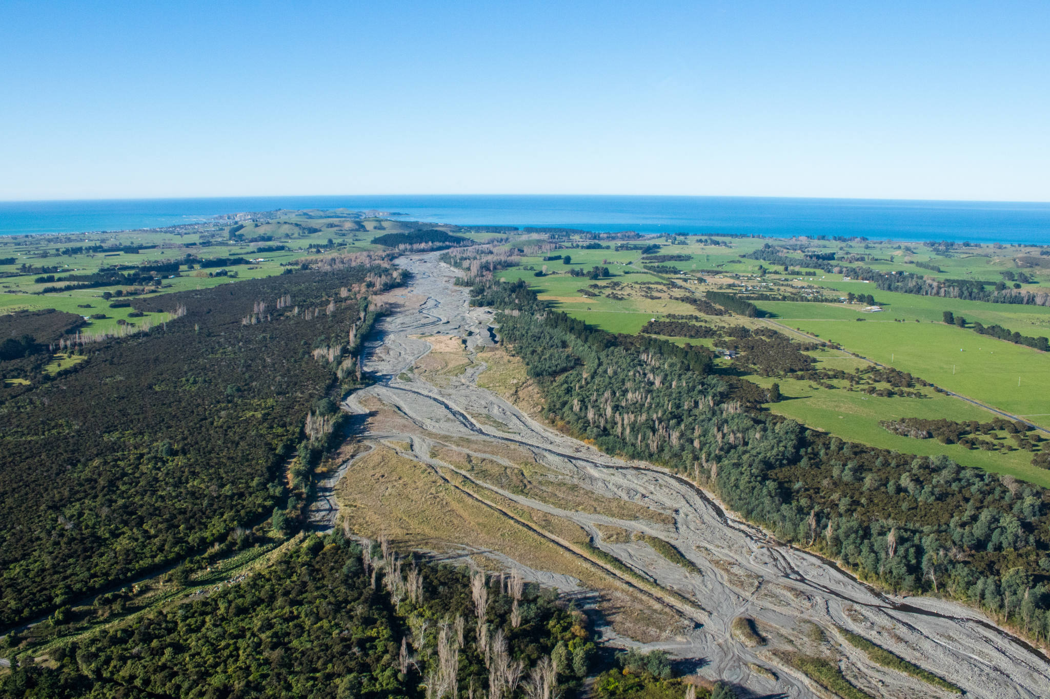 river braid between farmland reaching ocean