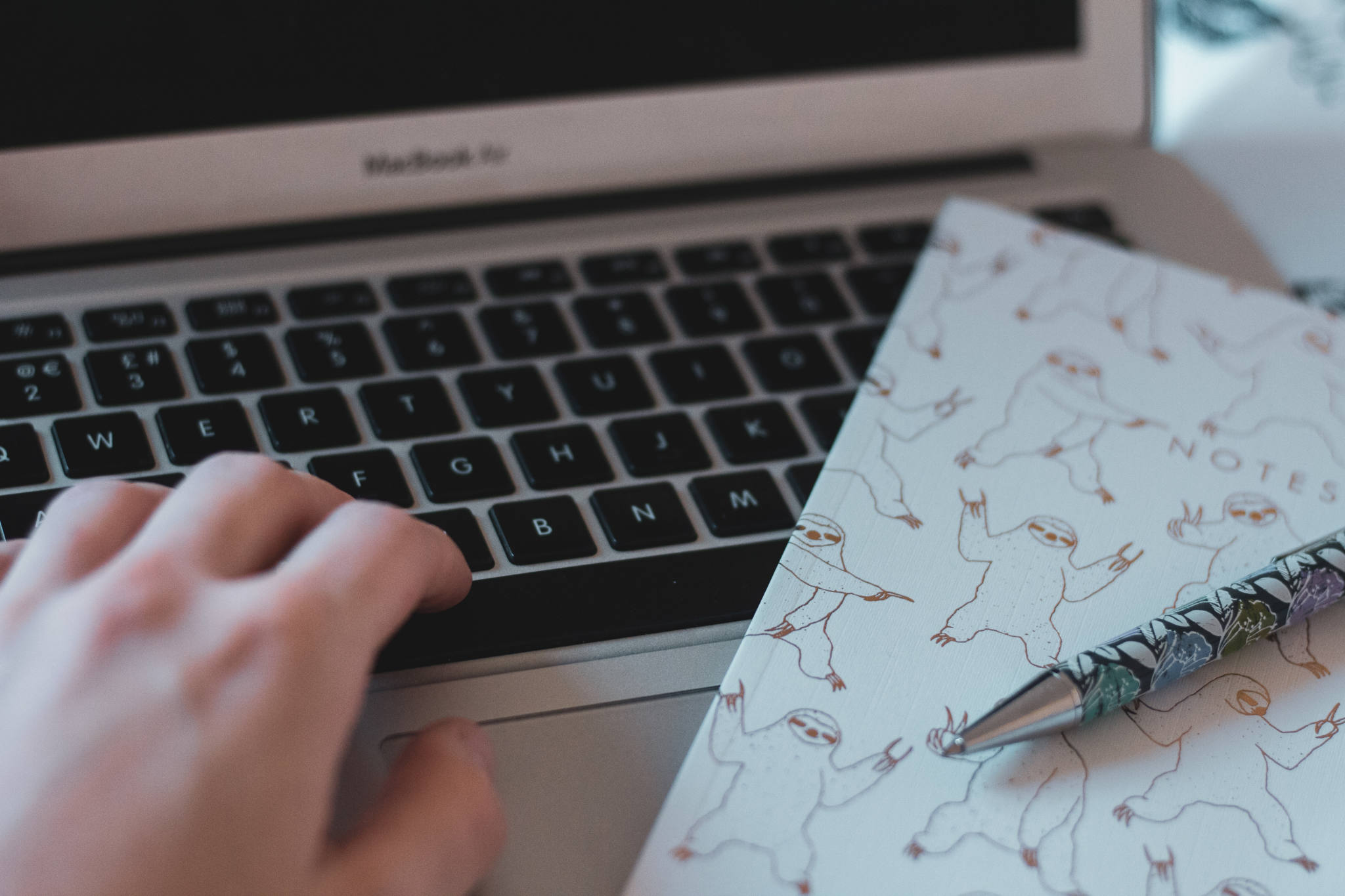 typing at laptop with notepad