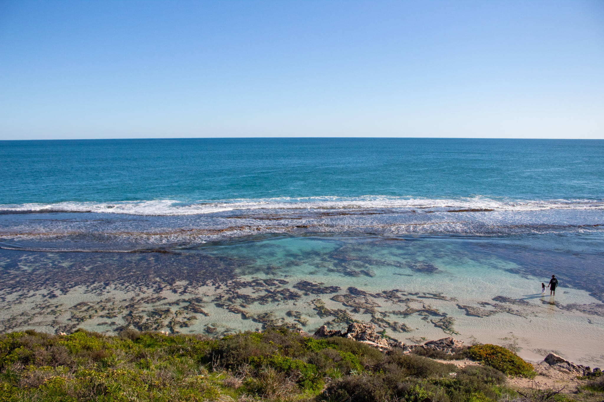 View overlooking Yanchep Lagoon as father and child paddle in water