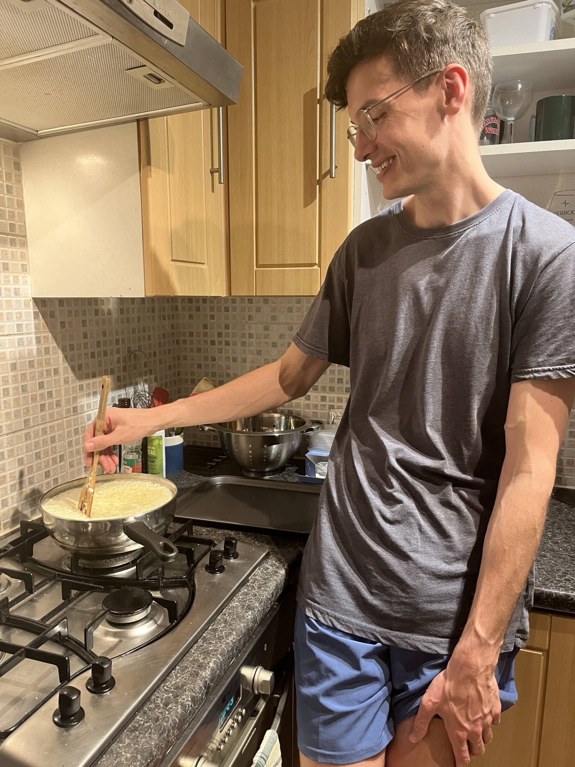 a man smiles while stirring a pot cooking on a stove